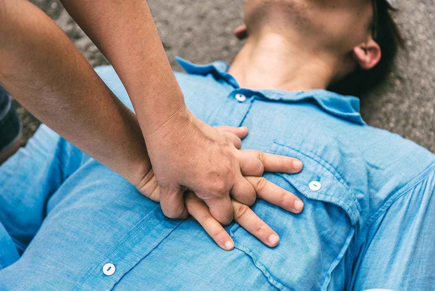 two hands clasped over a chest, performing CPR